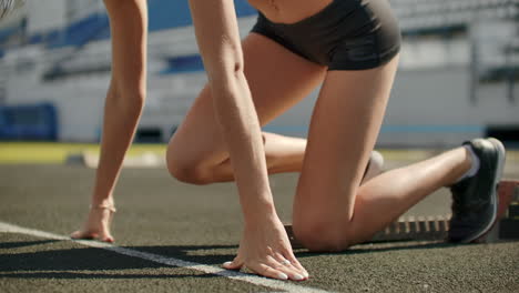 Slender-young-girl-athlete-is-in-position-to-start-running-in-the-pads-on-the-track-in-slow-motion